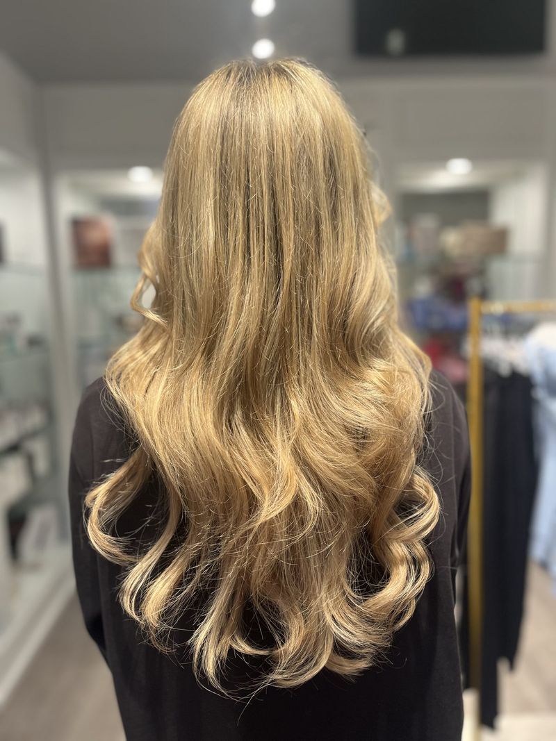 Full, long blonde extensions styled in soft waves